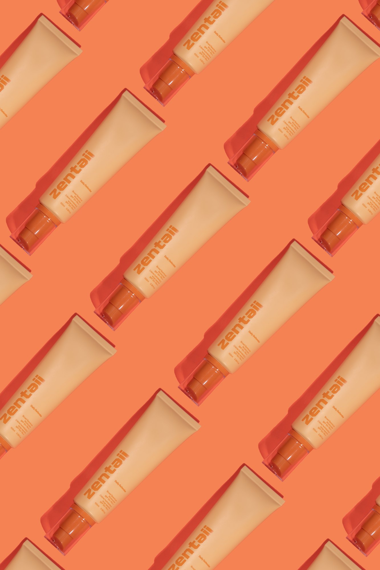 Daily Defender SPF tubes repeated in a diagonal grid on a saturated orange ground.